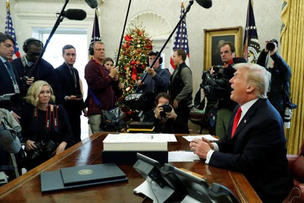 2017年12月22日，在美国华盛顿白宫，美国总统特朗普（右）签署减税法案后对媒体讲话。
